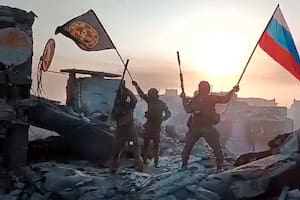 En esta imagen tomada de un video difundido por el Servicio de Prensa Prigozhin, integrantes de la compañía militar Grupo Wagner de Yevgeny Prigozhin ondean una bandera rusa y otra del Grupo Wagner en una estructura dañada en Bakhmut, Ucrania. (Servicio de Prensa Prigozhin vía AP)