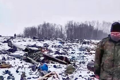 En esta imagen, tomada de un video distribuido por el Comité Investigador de Rusia el 26 de enero de 2024, un empleado de la agencia camina por un lugar con restos de un avión militar ruso Il-76 que se estrelló cerca de Yablonovo, en la región rusa de Belgorod, el 25 de enero de 2024. (Comité Investigador de Rusia vía AP)