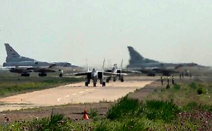 En esta imagen tomada de un video el lunes 10 de junio de 2024 y publicada por el servicio de prensa del Ministerio ruso de Defensa, dos cazas MiG-31 de la fuerza aérea rusa salen para una misión de entrenamiento con dos bombarderos Tu-22M3 de fondo durante maniobras conjuntas de Rusia y Bielorrusia para entrenar al ejército en el empleo de armas nucleares tácticas.