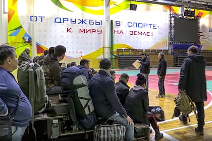 En esta imagen tomada de un video, los reclutas rusos se reúnen dentro de un estadio cubierto convertido en centro de recogida para los reclutas, que serán enviados a las unidades militares del Distrito Militar del Este, en Yakutsk, Rusia, el viernes 23 de septiembre de 2022.