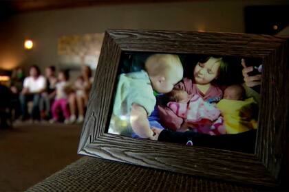 En esta imagen tomada de un video, se muestra una fotografía de los hijos de Matthew Rigney y Danielle Hall mientras son entrevistados en el fondo de la habitación, el lunes 23 de agosto de 2021, en Waverly, Tennessee. (WTVF vía AP)