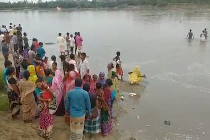 En esta imagen tomada de un video, varias personas buscan a sobrevivientes en el río Karatoa luego de que una embarcación sobrecargada naufragara allí el domingo 25 de septiembre de 2022, en Panchagarh, Bangladesh. (AP Foto)