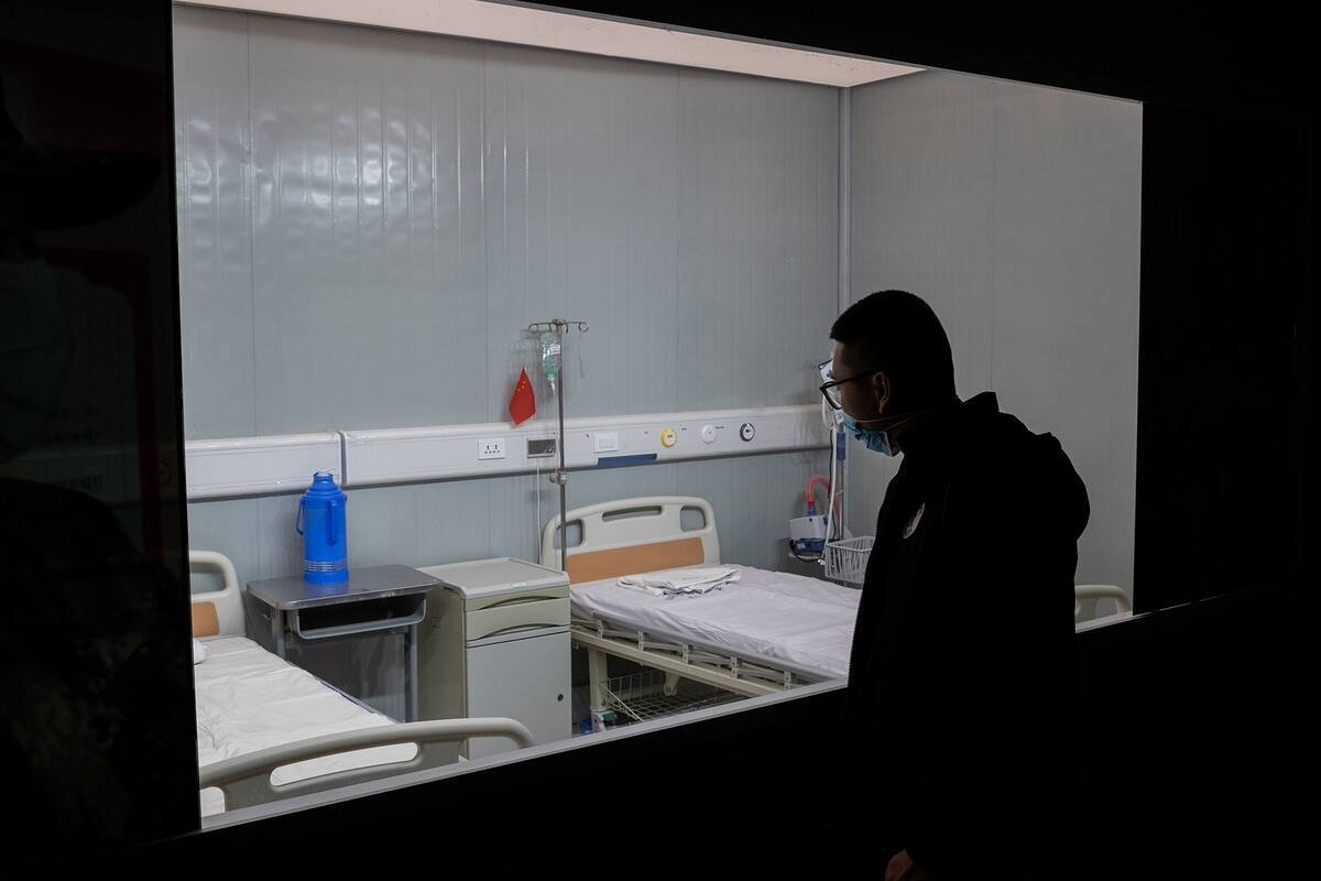 En esta imagen tomada el 15 de enero de 2021, un hombre mira las camas de un hospital en una exposición sobre la lucha de China contra el coronavirus en un centro de convenciones que anteriormente se utilizaba como hospital provisional para pacientes en Wuhan