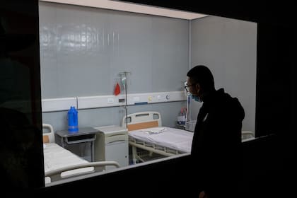 En esta imagen tomada el 15 de enero de 2021, un hombre mira las camas de un hospital en una exposición sobre la lucha de China contra el coronavirus en un centro de convenciones que anteriormente se utilizaba como hospital provisional para pacientes en Wuhan