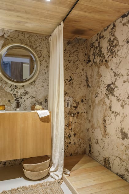 En este baño diseño de Talleres Sustentables se eligió ablandar la piedra con madera en el vanitory, el deck de ducha y el cielo raso.