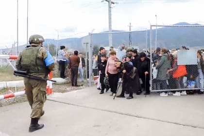 En este captura de video tomada de un material distribuido por el Ministerio de Defensa ruso el 21 de septiembre de 2023, un miembro de la fuerza de paz rusa hace guardia mientras civiles armenios ingresan a una base militar rusa cerca de Stepanakert en la región de Nagorno Karabaj.