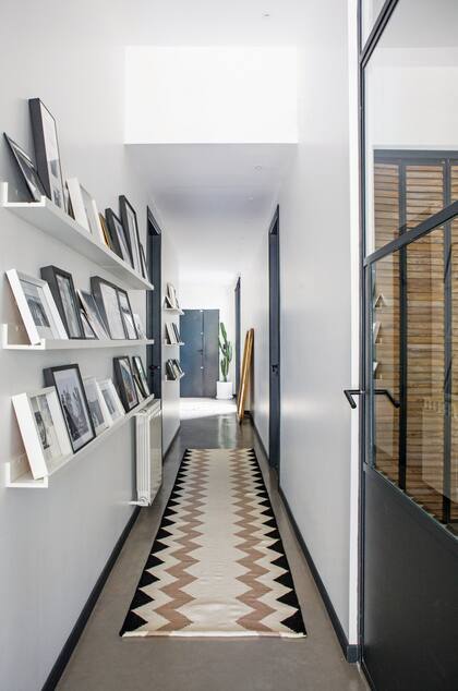 En este departamento, se colocaron una serie de cuadros de diferentes marcos y tamaños y fotos en blanco y negro. Estantes de madera (Ikea) y alfombra de lana (Elementos Argentinos).