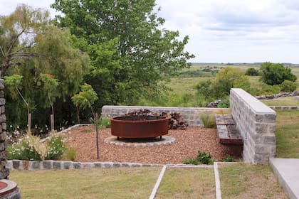 En este jardín aterrazado en el cerro, se destaca la visual desde el fogón hacia el campo. El respaldo es también muro de contención de las terrazas del jardín y el asiento es de madera de durmientes de ferrocarril