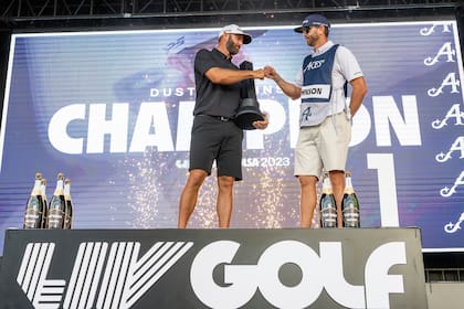 En foto del 14 de mayo del 2023, l campeón individual Dustin Johnson y su caddie Austin Johnson celebra en el podio durante la ceremonia de trofeo en el torneo LIV Golfen el Cedar Ridge Country Club de Tulsa