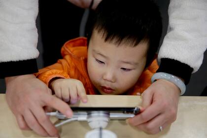 Un chico juega con un celular mientras sus padres realizan compras durante el Black Friday
