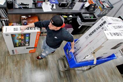 Un hombre lleva los televisores que compró a la línea de cajas en una tienda Best Buy
