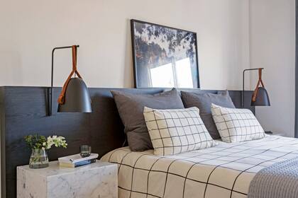 En la cama, acolchado a cuadros (Urban Outfitters), almohadones y pie de cama gris (todo, De Arrieta)