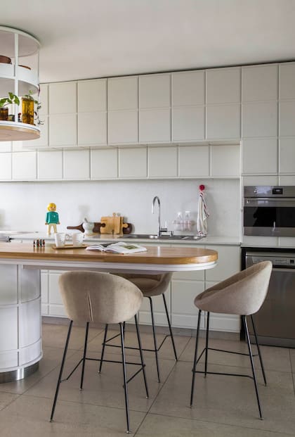 En la cocina, la pata de la isla con barra volada comparte el lenguaje de los muebles bajomesada y las alacenas, todos diseños de Irizar Kon.