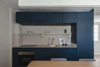 En la cocina, mueble de melamina ‘Tuareg’ (Faplac) con mesada y alzada de Purastone ‘Limestone’ (Marmolería Gaona). Bacha ‘Quadra Q40’ (Johnson Acero), grifería monocomando ‘Puelo’ (FV). Anafe (Teka) y horno (Longvie), ambos eléctricos. En el estante, un artefacto de iluminación ‘h 473’ de Huup (Griscan).