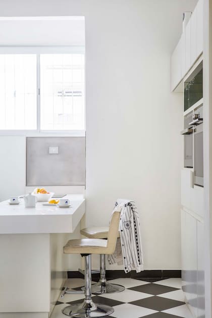 En la cocina, muebles laqueados en blanco, alzadas y electrodomésticos de acero se combinaron con unos pisos dameros que le dan un toque de calidez.