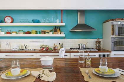 En la cocina, piso pintado de blanco, luminarias con forma de bola, enorme isla, mesada de lapacho y alzada de azulejos ‘Subway’.