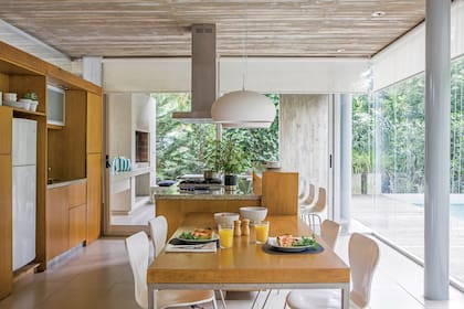 En la cocina se alinean mesa, isla y la parrilla en la galería. Campana de acero inoxidable (TST).