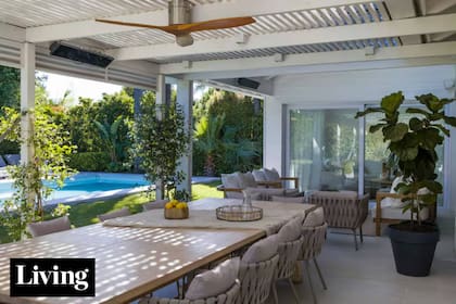 En la galería de @aloha_paisajismo, techo con caños rectangulares que arman una grilla. La mesa en madera maciza, diseño de Estudio Flombaum, se acompañó con unas sillas y un ventilador de diseño importados (similares, en Ventto)