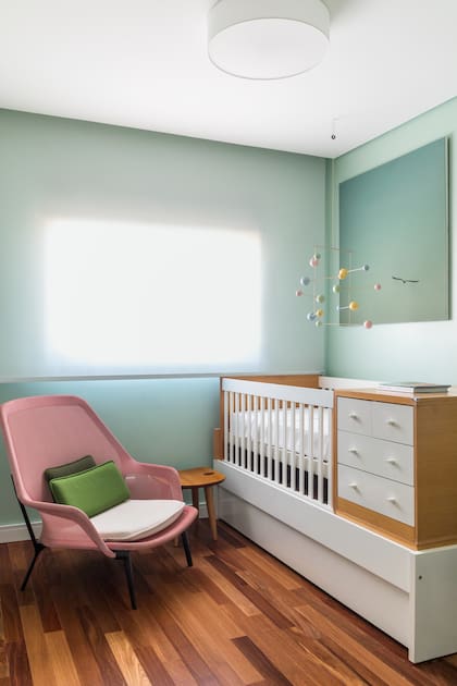 En la habitación infantil, verde agua y rosa son los tonos principales para contrastar con el blanco y la madera. La obra fue hecha por Lívia.