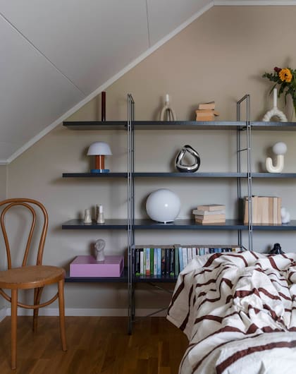 En la habitación vuelve a aparecer uno de sus recursos preferidos: estanterías abiertas con objetos de diseño.