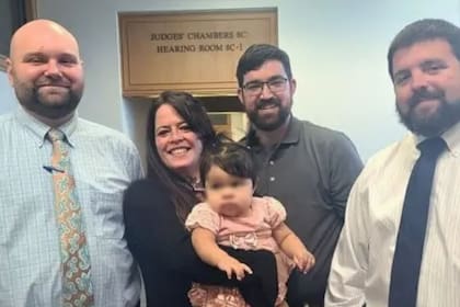 En la imagen, dos miembros de la Policía del Condado de Polk, en Florida, posan junto con los nuevos padres adoptivos de la pequeña