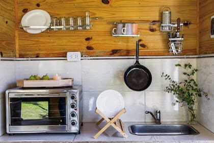 Hay espacio suficiente para una bacha y un hornito eléctrico: Acompañan un secaplatos de bambú color natural y una bandeja de madera (todo de Arredo).
