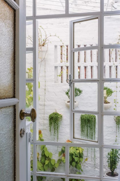 El baño iba a tener una ventana pequeña, pero al confirmar que se podía demoler la pared, optó por un ventanal de vidrio repartido que llega hasta el piso que integra el patio al entrepiso.