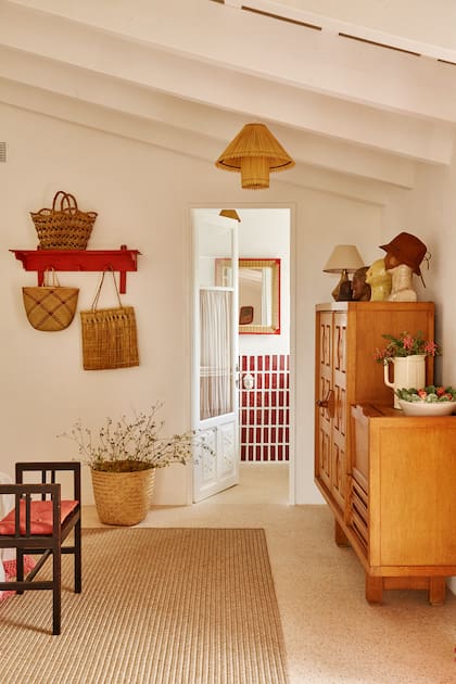 En la repisa, los tapizados y adornos se repite la paleta. El revestimiento del baño se colocó de modo vertical con un rojo dominante.