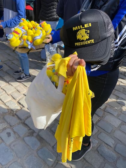En las inmediaciones del Cabildo de Córdoba, y a la espera del presidente Javier Milei, vendedores comercializan el tradicional patito kawaii (que se usa sobre la cabeza o en las prendas) con una bandera patria que les rodea el cuello