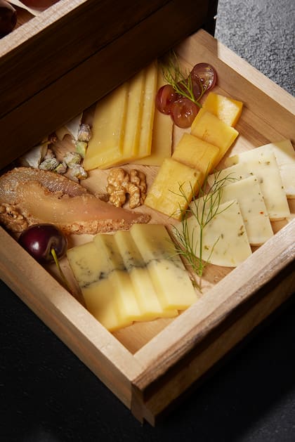 En las tablas de quesos hay variedades como queso brie, musters, mimolette y gascogne junto a almendras, uvas, dátiles, tomates secos y gremolata de peras, además de miel especiada