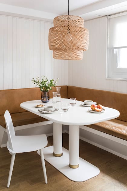 En línea con una paleta de colores neutros, el banco del box fue tapizado en cuero natural tinte suela. La mesa de comedor, es de MDF con pintura poliuretánica gofratto, un tipo de laqueado más resistente que el tradicional. Lámpara colgante ‘Sinnerlig’ de Ilse Crawford (Ikea).