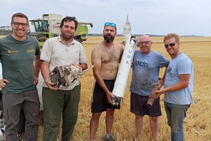 En Lobería, los contratistas sostienen las partes del cohete encontrado en medio de un lote de trigo