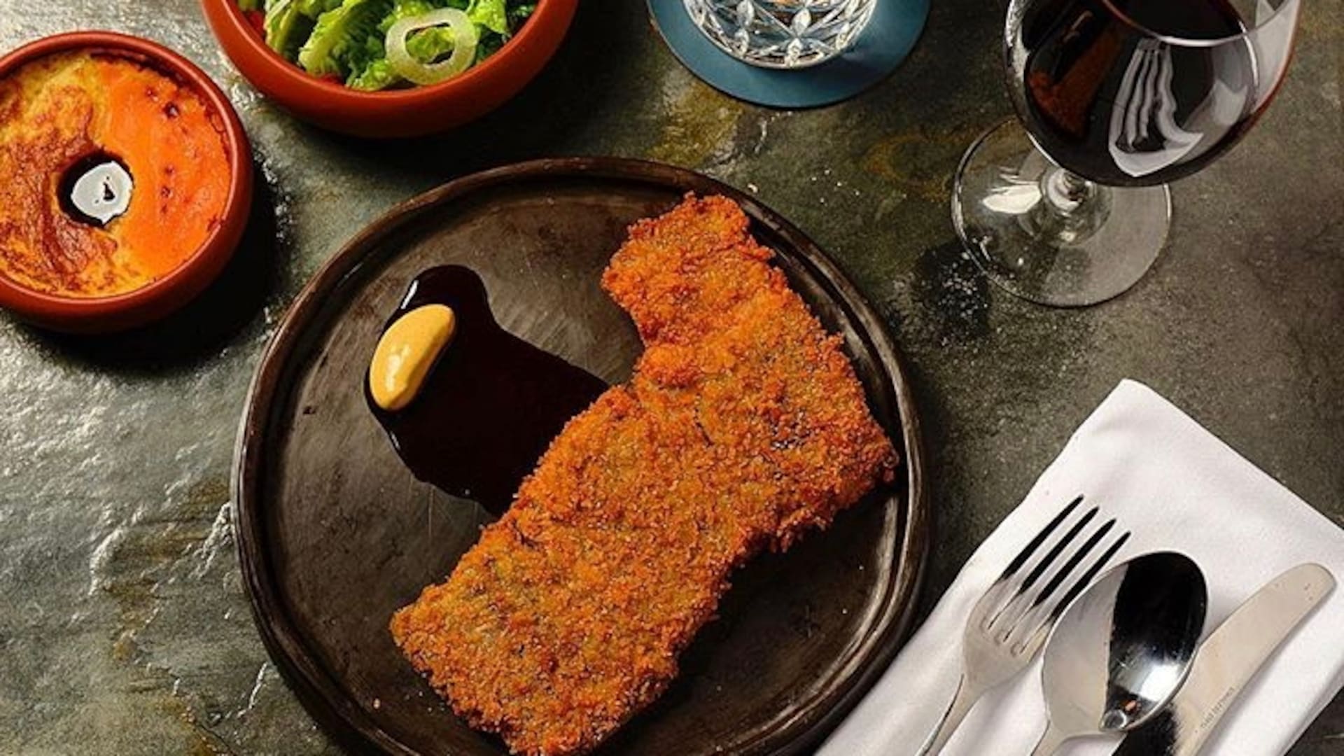 La carne de la milanesa es tapa de asado de wagyu cocida al vacío por 10 horas, empanada en panko antes de freír