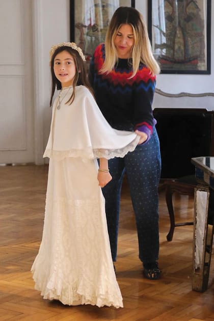 En plena prueba del vestido. Fucsia sonríe mientras su mamá ultima los detalles del vestido con capa que le hizo para su primera comunión