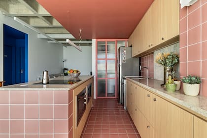 En pocos metros, resolvieron una nueva circulación para lograr una cocina moderna y funcional, pensada para recibir visitas. La corrediza en hierro rosa y vidrio acanalado, una decisión ingeniosa para ocultar el lavadero sin perder amplitud.