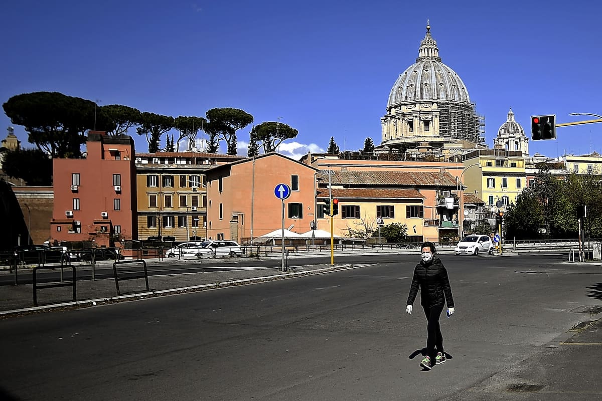 En soledad, un persona camina frente a la basílica San Pedro; las calles de Italia siguen vacías, como desde hace 26 días