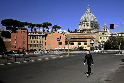 En soledad, un persona camina frente a la basílica San Pedro; las calles de Italia siguen vacías, como desde hace 26 días