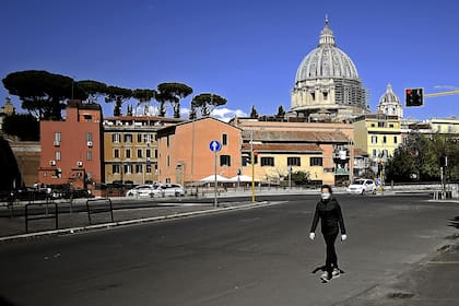En soledad, un persona camina frente a la basílica San Pedro; las calles de Italia siguen vacías, como desde hace 26 días por la cuarentena para intentar contener el coronavirus