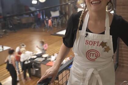 De fondo se ve la imagen de la estación de cocina de Claudia Villafañe, rodeada de personas