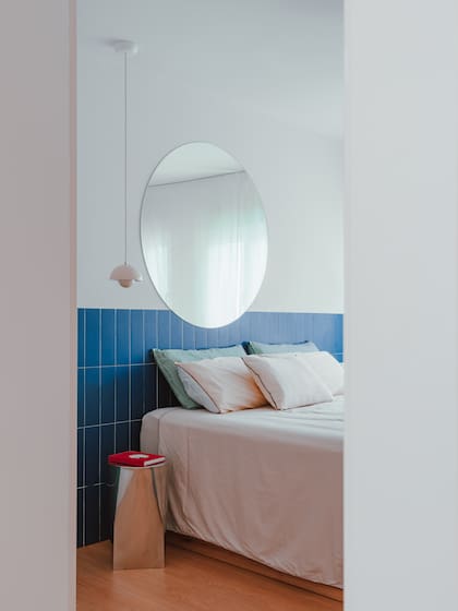 En un dormitorio, un espejo circular en el cabecero juega con los reflejos.