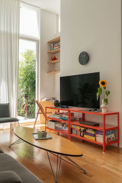En un rincón del living, aprovecharon un nicho para generar una biblioteca con un mini escritorio. Para apoyar la tele, dos nuevas mesas con estantes de Caos.