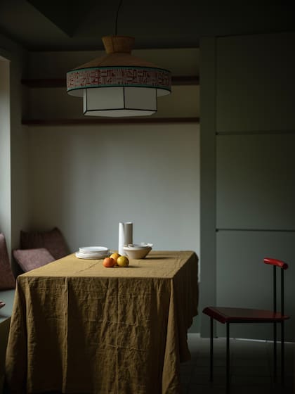 En un rincón íntimo de la cocina, un banco empotrado bajo la ventana y una mesa pequeña ofician de comedor diario. Lámpara colgante ‘Giardino’ (Servomuto).