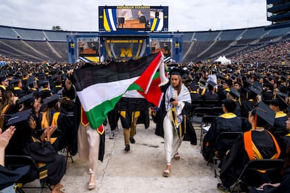 En una ceremonia de graduación en la Universidad de Michigan en un estadio, egresadas Hamamy exhiben una bandera de Palestina; las protestas contra Israel se expanden.