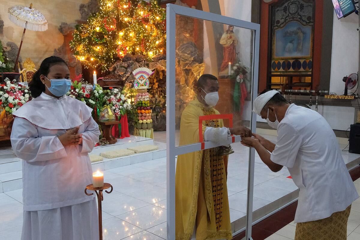 En una iglesia de Bali, Indonesia usan protectores de plástico en la celebración por navidad