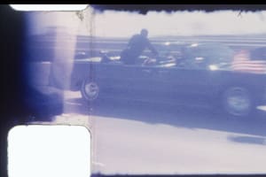 En una instantánea tomada de una filmación se ve a Clint Hill, un agente del Servicio Secreto, encima del auto que llevaba al presidente John F. Kennedy al hospital tras ser tiroteado en Dallas el 22 de noviembre de 1963. Durante décadas, la película tomada por Dale Carpenter ha sido una reliquia familiar, y rara vez vista por personas ajenas a la familia; en septiembre de 2024, RR Auction la pondrá a la venta. (RR Auction via The New York Times)
