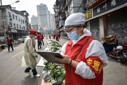 En Wuhan, voluntarias chequean el estado de verduras para entregarlas a la población