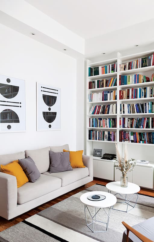 Joy y su marido en el living equipado con un amplio sofá (Loft) y dúo de sillones individuales heredados. La biblioteca (Melazza) es un diseño de Ideï. Los cuadros también son obra de ella.