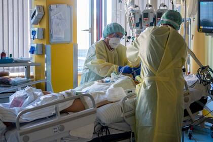 Enfermeras de la unidad de cuidados intensivos tratan a un paciente grave de COVID-19 en la UCI del hospital universitario en Halle/Saale, Alemania, el 22 de noviembre de 2021. (Hendrik Schmidt/dpa vía AP)