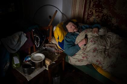 Enfermo de cáncer, Gennadiy Shaposhnikov, de 83 años, descansa en su casa parcialmente destruida por un cañoneo ruso en otoño pasado en Kalynivske, Ucrania, sábado 28 de enero de 2023. (AP Foto/Daniel Cole)