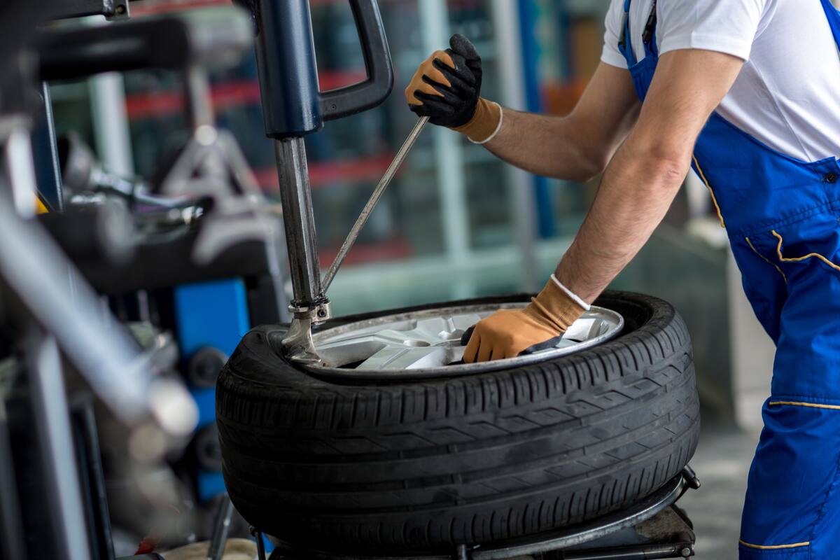 engineer balancing car wheel on balancer in workshop
